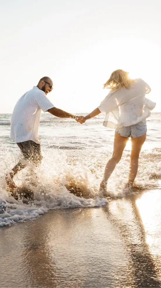 Couple jouant sur la plage au coucher du soleil.