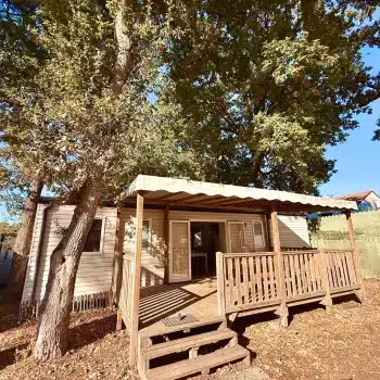 Mobil-home avec terrasse en bois ombragée.