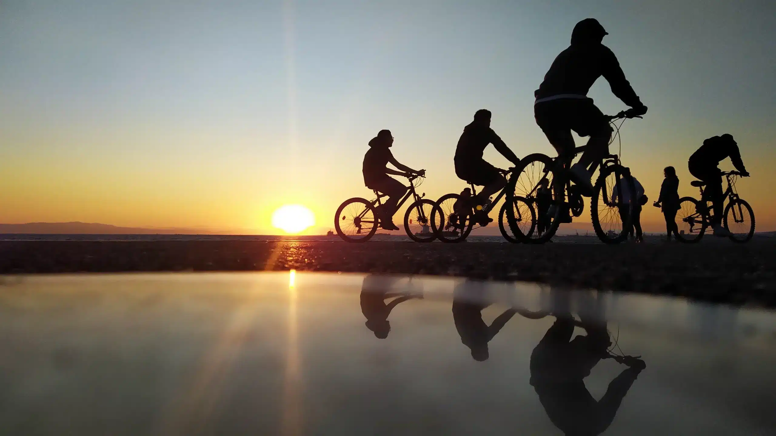 Cyclistes au coucher de soleil, reflets sur l'eau.