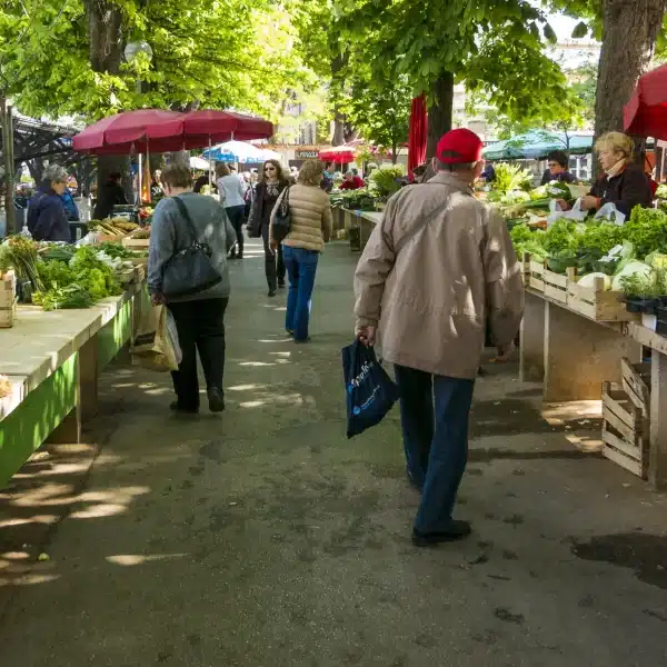 Marché en plein air avec légumes et clients.