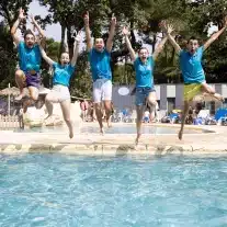 Personnes sautant joyeusement dans une piscine.
