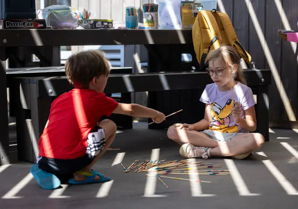 Enfants jouant au Mikado dans la lumière du soleil.