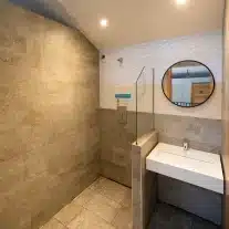 Douche moderne avec lavabo et miroir circulaire.