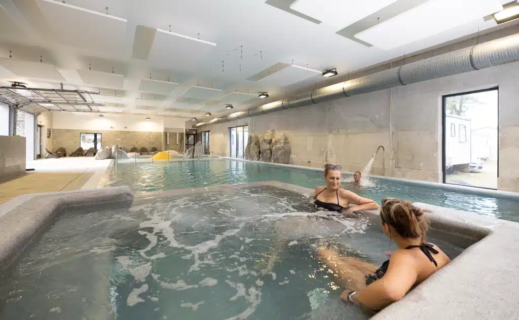Piscine intérieure avec bains à remous, personnes relaxant.
