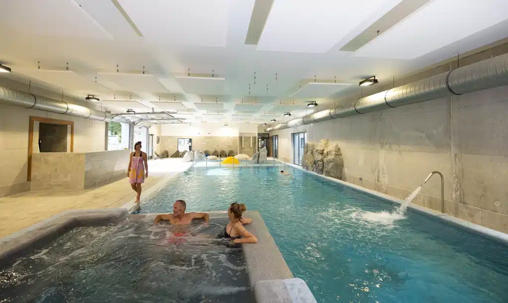 Piscine intérieure moderne avec jacuzzi et personnes détendues.