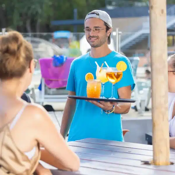 Serveur apportant des boissons en terrasse.