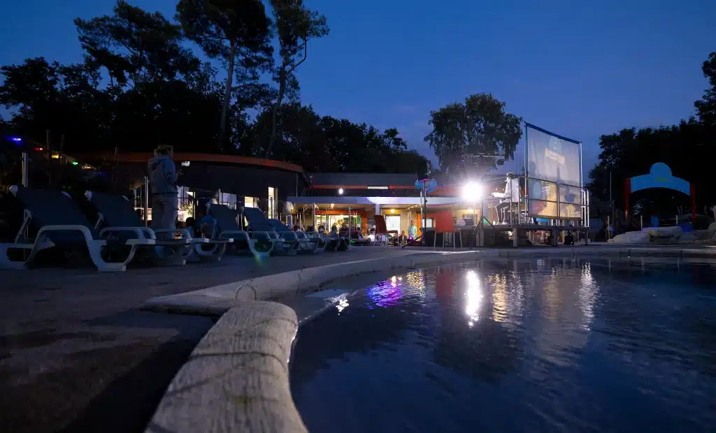 Piscine éclairée la nuit avec écran cinéma