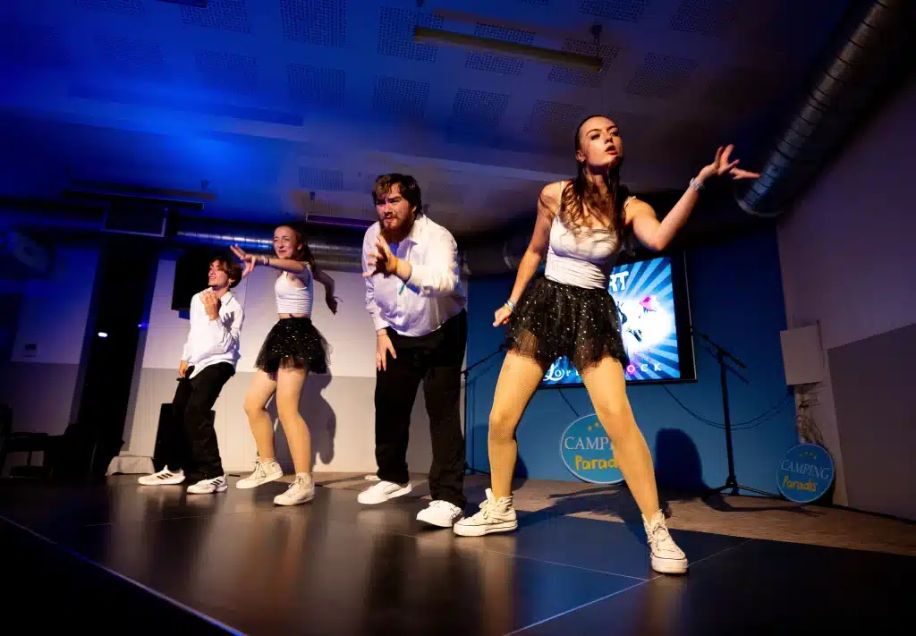 Danseurs sur scène avec éclairage bleu.