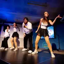 Danseurs sur scène avec éclairage bleu.