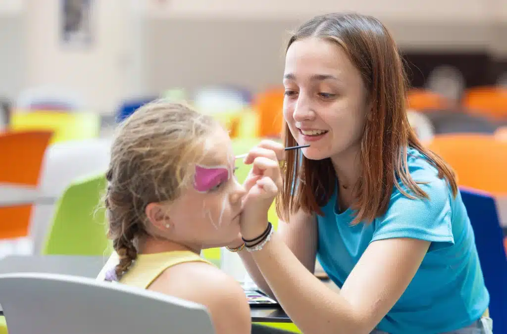 Femme maquillant le visage d'une fille.