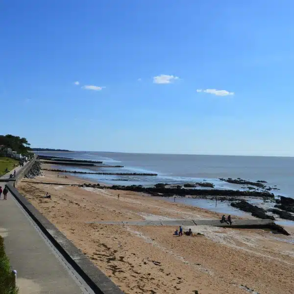 Promenade et plage en bord de mer ensoleillée.
