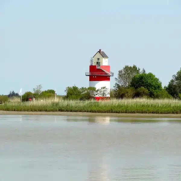 Phare rouge et blanc au bord de l'eau.
